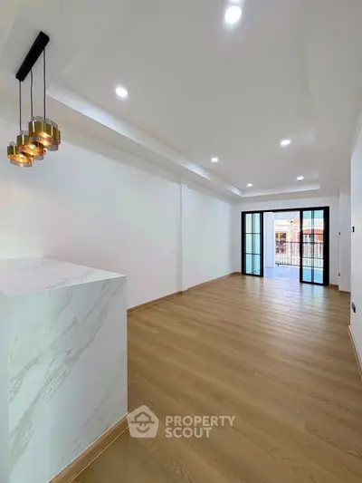 Spacious modern living room with elegant lighting and large windows opening to a balcony.