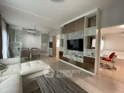Modern open-plan living room with elegant decor and dining area, featuring a stylish TV wall unit.