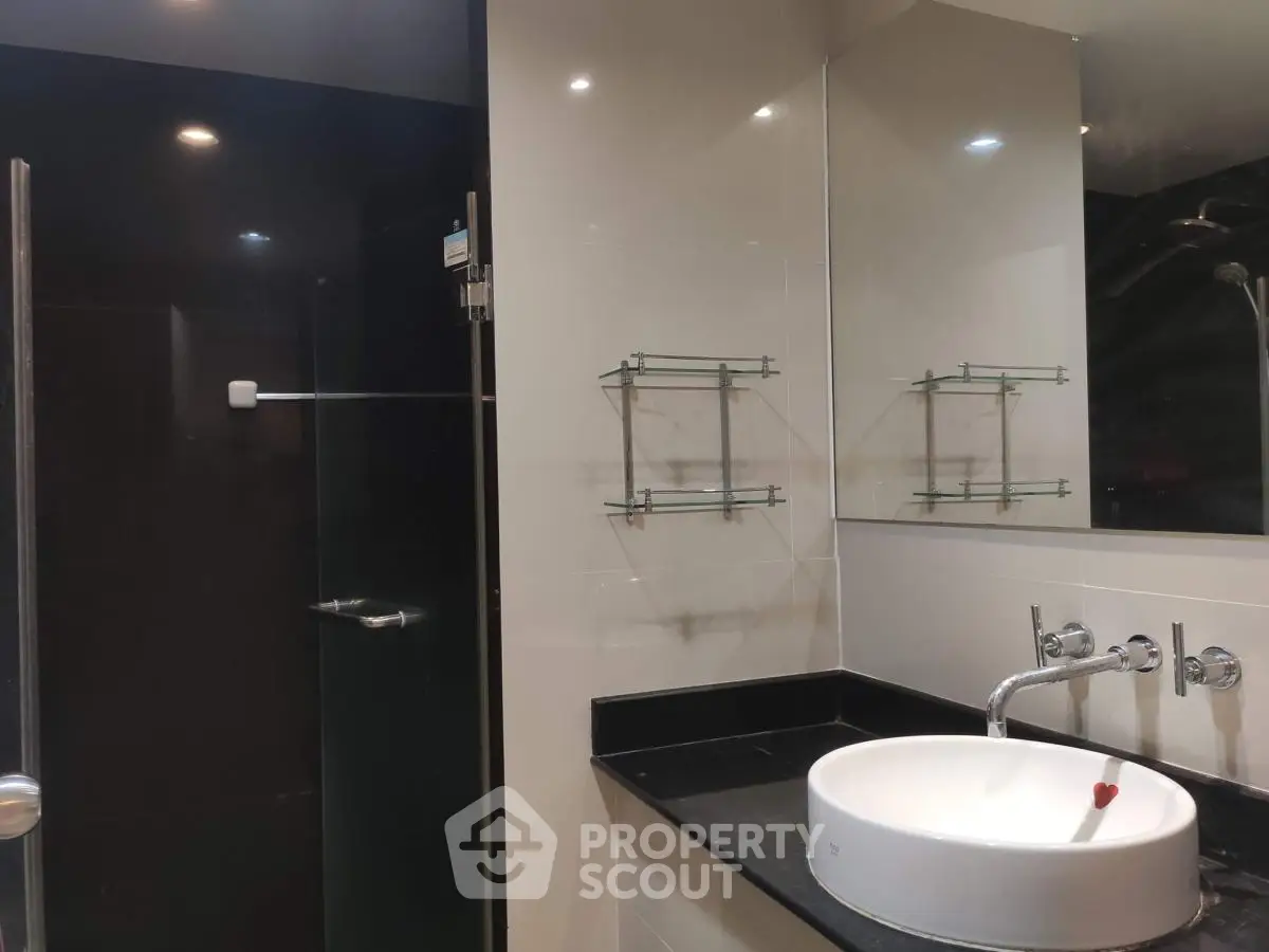 Modern bathroom with sleek black countertop and glass shower enclosure