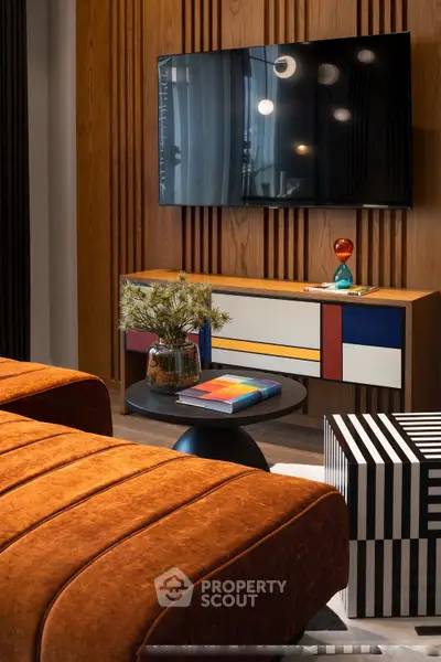 Stylish modern living room with vibrant decor and wall-mounted TV, perfect for contemporary urban living.