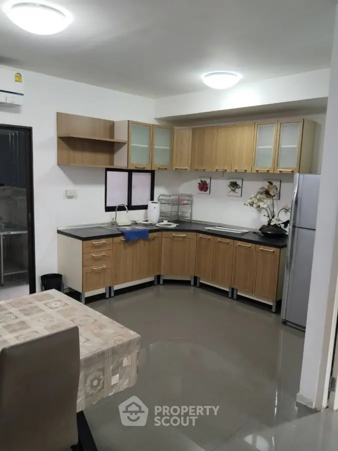 Modern kitchen with wooden cabinets and sleek appliances in a cozy apartment.