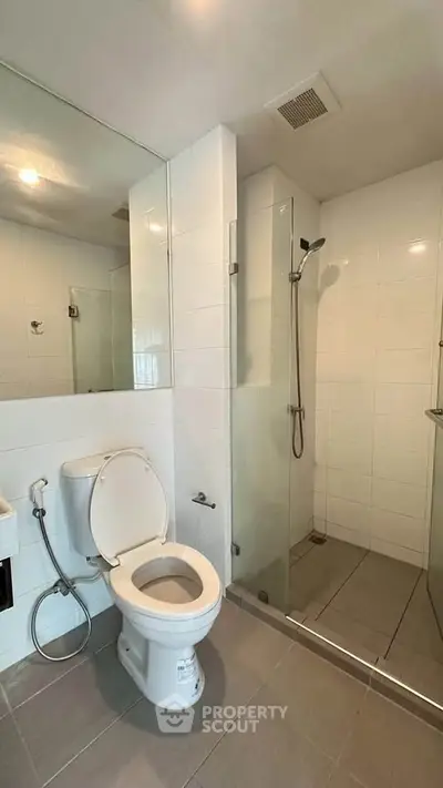 Modern bathroom with sleek shower and toilet in a contemporary apartment.