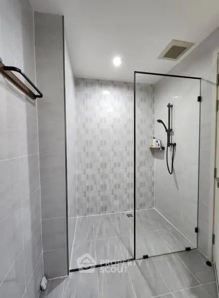 Modern bathroom with sleek glass shower enclosure and stylish gray tiles.