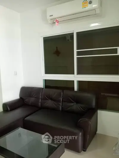Modern living room with sleek leather sofa and air conditioning unit, perfect for comfort and relaxation.