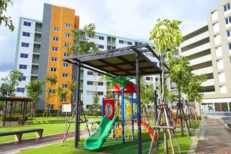 Modern apartment complex with vibrant playground and lush green surroundings.