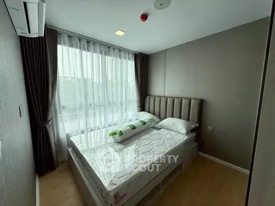Modern bedroom with large window and stylish decor in a real estate property.