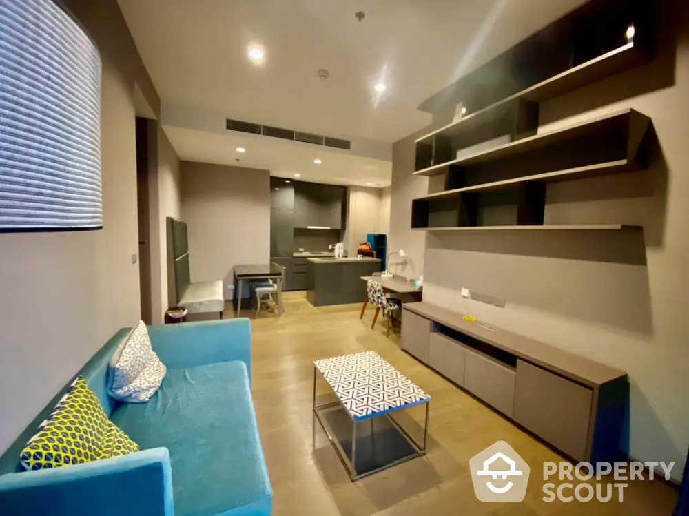 Modern living room with open kitchen and stylish shelving in a cozy apartment.