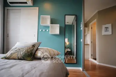 Modern bedroom with teal accent wall and stylish decor in a cozy apartment.
