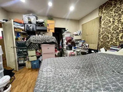 Cluttered bedroom with storage boxes and patterned wall decor