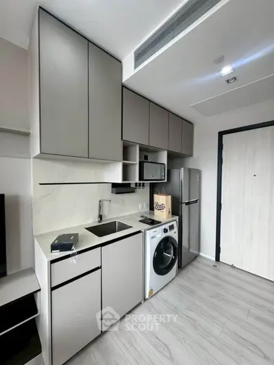 Modern compact kitchen with sleek cabinetry and built-in appliances in a stylish apartment.