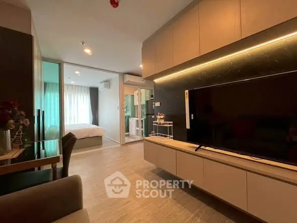 Modern living room with sleek TV unit and view into cozy bedroom