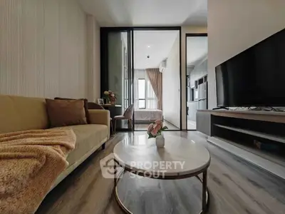 Modern living room with cozy sofa, stylish coffee table, and large TV, leading to a bright bedroom.