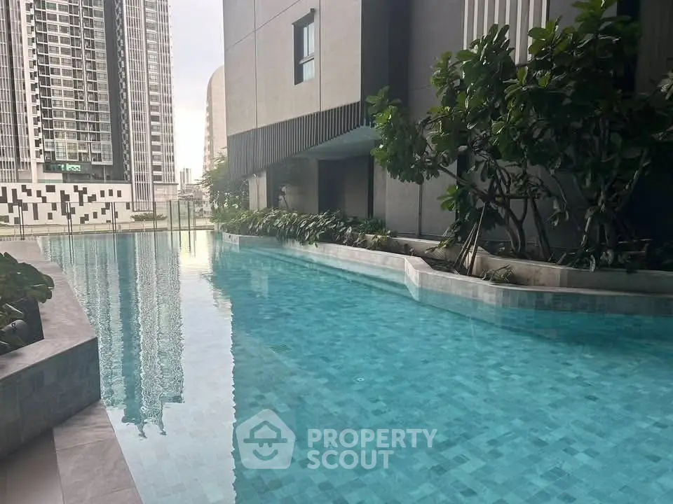 Luxurious modern apartment pool with cityscape view and lush greenery.