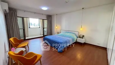 Spacious bedroom with modern decor and city view, featuring cozy seating area and elegant lighting.