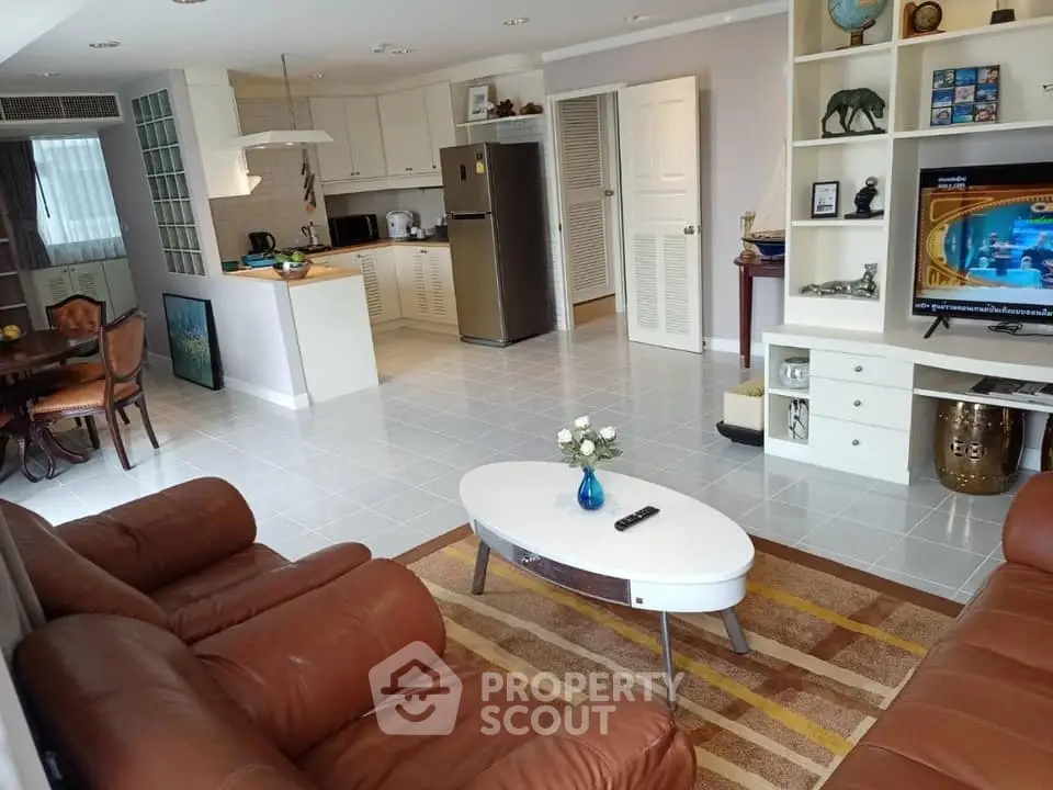 Spacious living room with open kitchen, leather sofas, and modern decor in a cozy apartment.