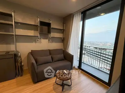 Modern living room with balcony and city view, featuring sleek furniture and open shelving.