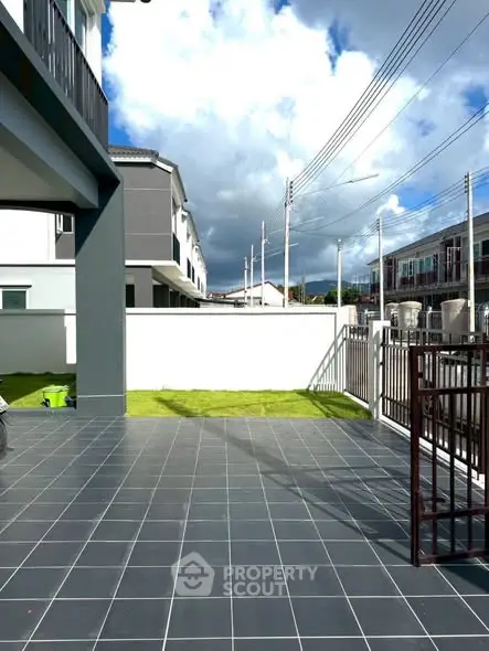 Spacious modern patio with tiled flooring and garden view in suburban neighborhood.