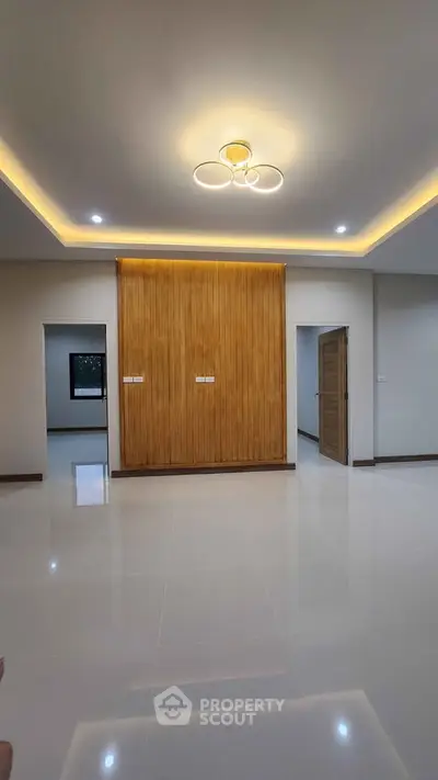 Spacious modern living room with elegant ceiling lighting and wooden accent wall