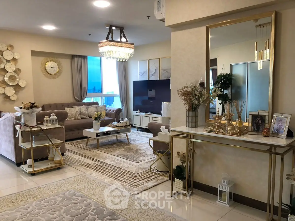 Luxurious living room with elegant decor and large TV, featuring plush sofas and stylish lighting.
