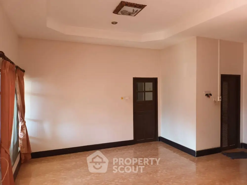 Spacious empty room with tiled floor and natural light, ideal for customization.