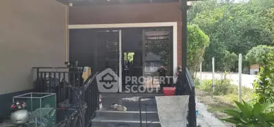 Charming home entrance with lush greenery and spacious patio, perfect for relaxation and outdoor activities.