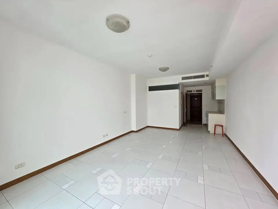 Spacious unfurnished apartment with tiled flooring and open kitchen layout.