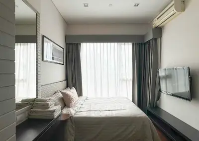 Cozy bedroom with modern decor, large window, and wall-mounted TV in a stylish apartment.