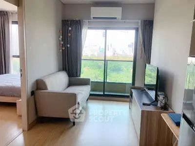 Modern living room with natural light and city view, featuring a cozy sofa and TV setup.