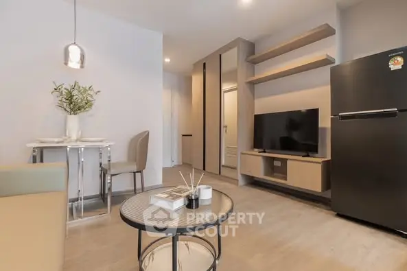 Modern living room with sleek furniture and open layout, featuring a TV and dining area.