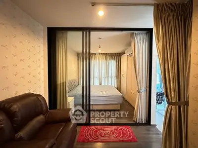 Modern apartment with sliding glass doors separating living room and bedroom, featuring elegant curtains and cozy decor.
