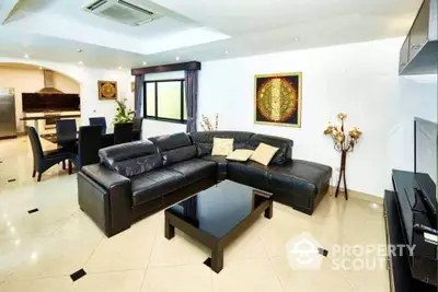 Spacious modern living room with black leather sofa and open kitchen layout