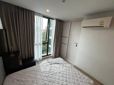 Modern bedroom with large window and air conditioning in a stylish apartment.
