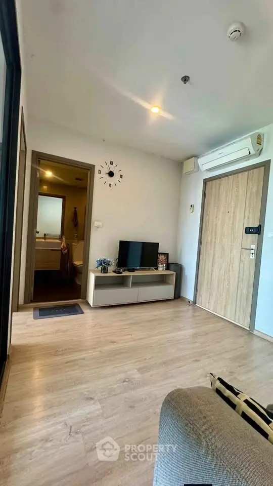 Modern living room with wooden flooring, TV unit, and air conditioning in a cozy apartment.