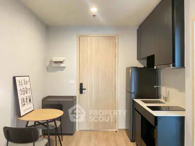 Modern compact kitchen with sleek black cabinets and small dining area.