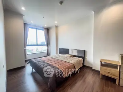 Spacious bedroom with city view and modern furnishings in a high-rise apartment.