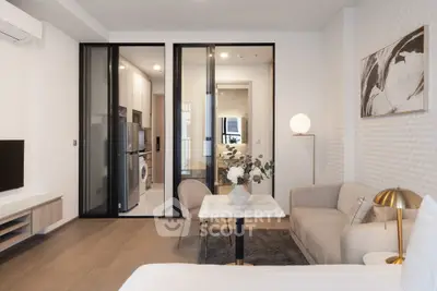 Modern living room with elegant decor and sliding glass doors leading to a sleek kitchen area.