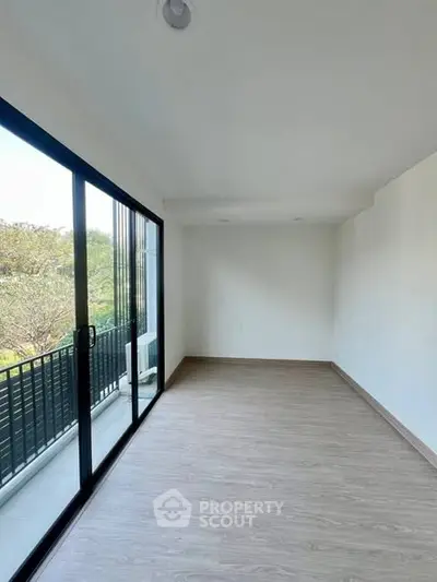 Spacious empty room with large sliding glass doors leading to a balcony with a serene view.