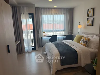 Modern bedroom with stylish decor and natural light, featuring a cozy bed and workspace.