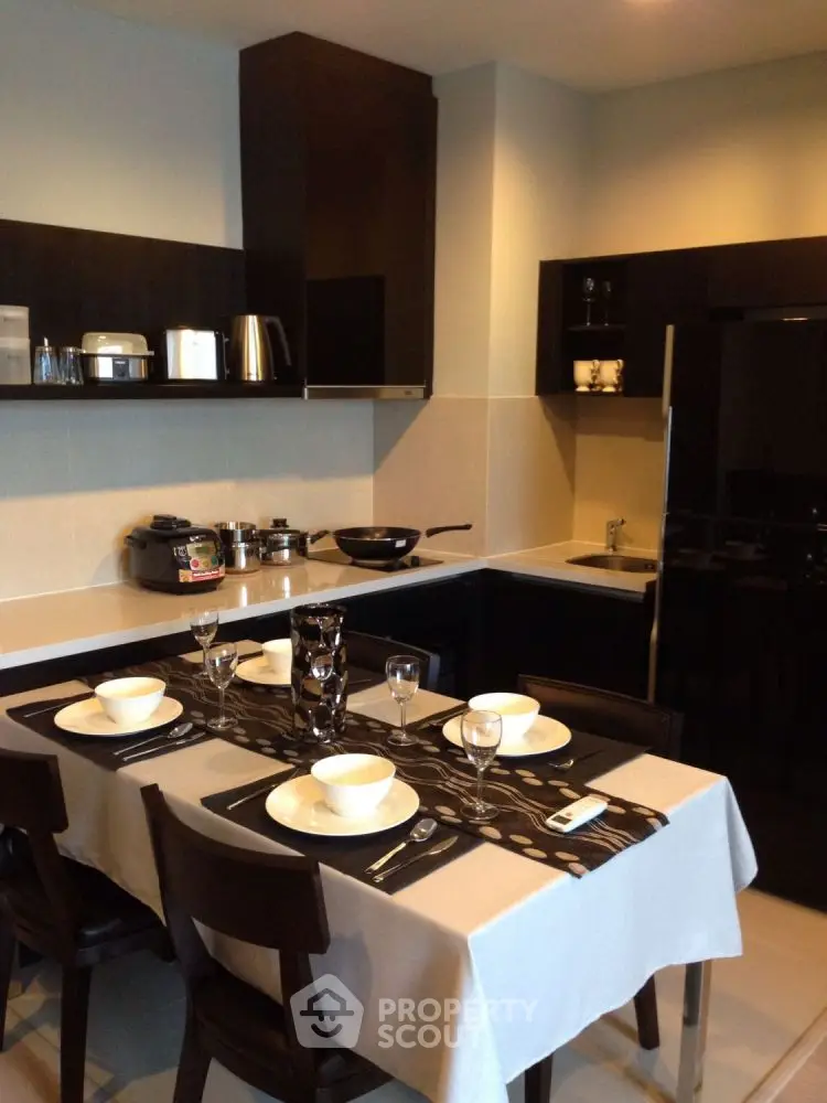 Modern kitchen with dining table, sleek cabinets, and appliances.