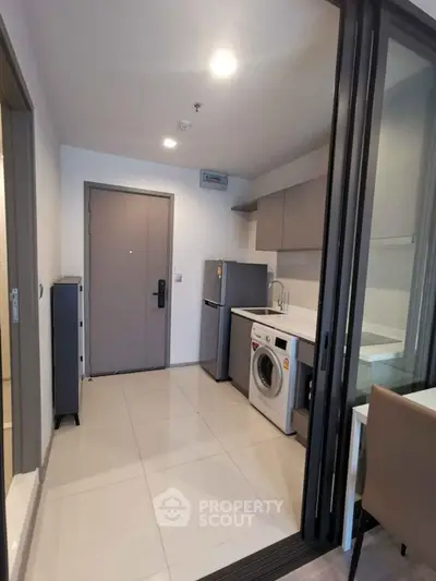 Modern kitchen with washing machine and fridge in compact apartment