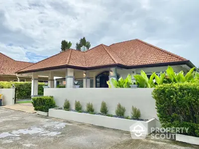 Charming single-story home with red-tiled roof and lush garden in serene neighborhood.