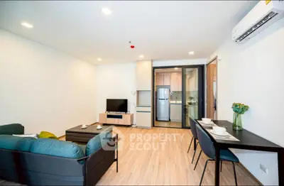 Modern living room with open kitchen, stylish furniture, and air conditioning.