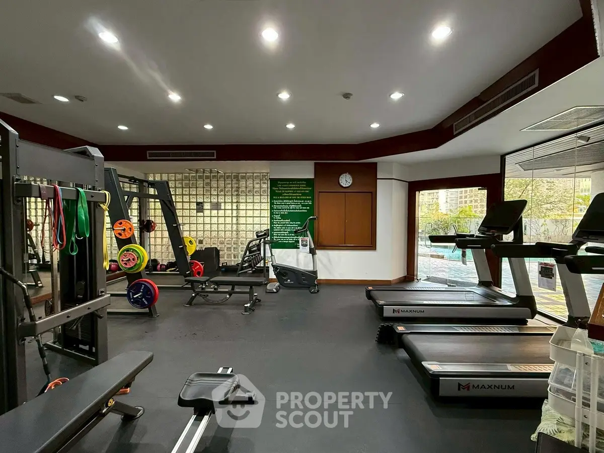 Spacious modern gym with state-of-the-art equipment and large windows for natural light.