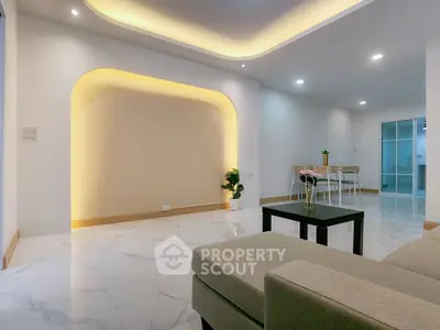 Modern living room with elegant lighting and stylish furniture, featuring a cozy dining area and sleek marble flooring.