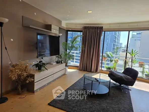 Modern living room with large windows and balcony view, featuring stylish furniture and indoor plants.