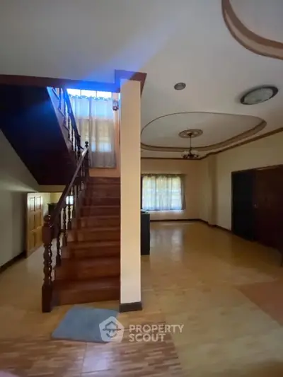 Spacious living area with wooden staircase and elegant ceiling design