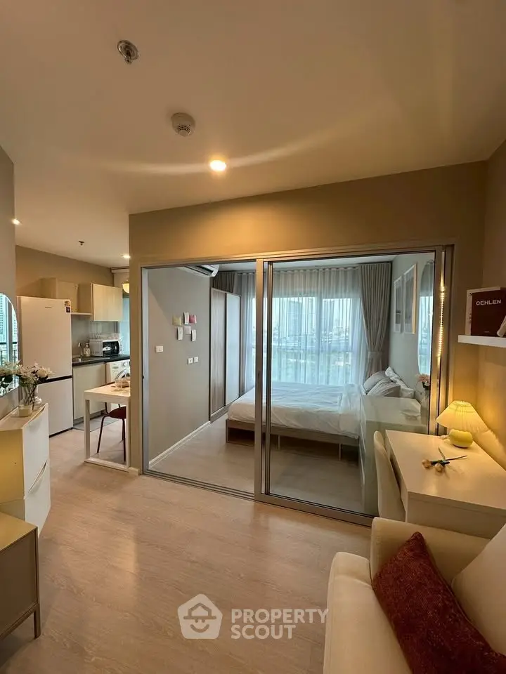 Modern studio apartment with open layout and cozy bedroom separated by glass doors.