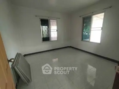 Spacious empty room with tiled flooring and two windows, ideal for customization.
