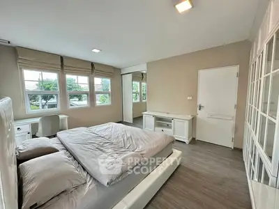 Spacious bedroom with large windows and modern furnishings, offering a bright and inviting atmosphere.
