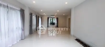 Spacious and bright living room with large windows and elegant curtains